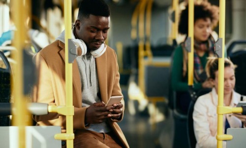 A man using his phone while riding on a bus.