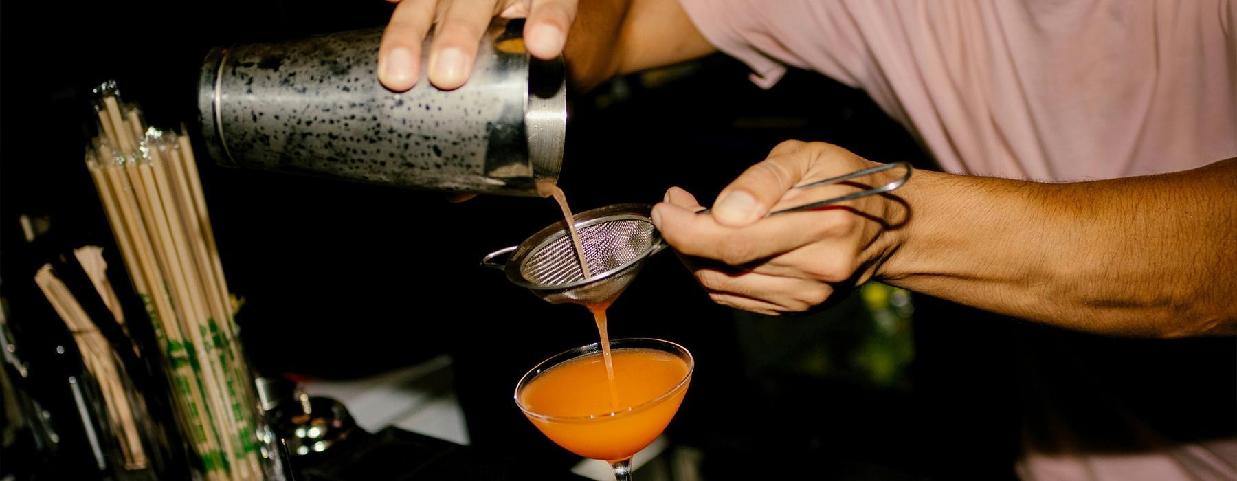a person pouring a drink into a glass